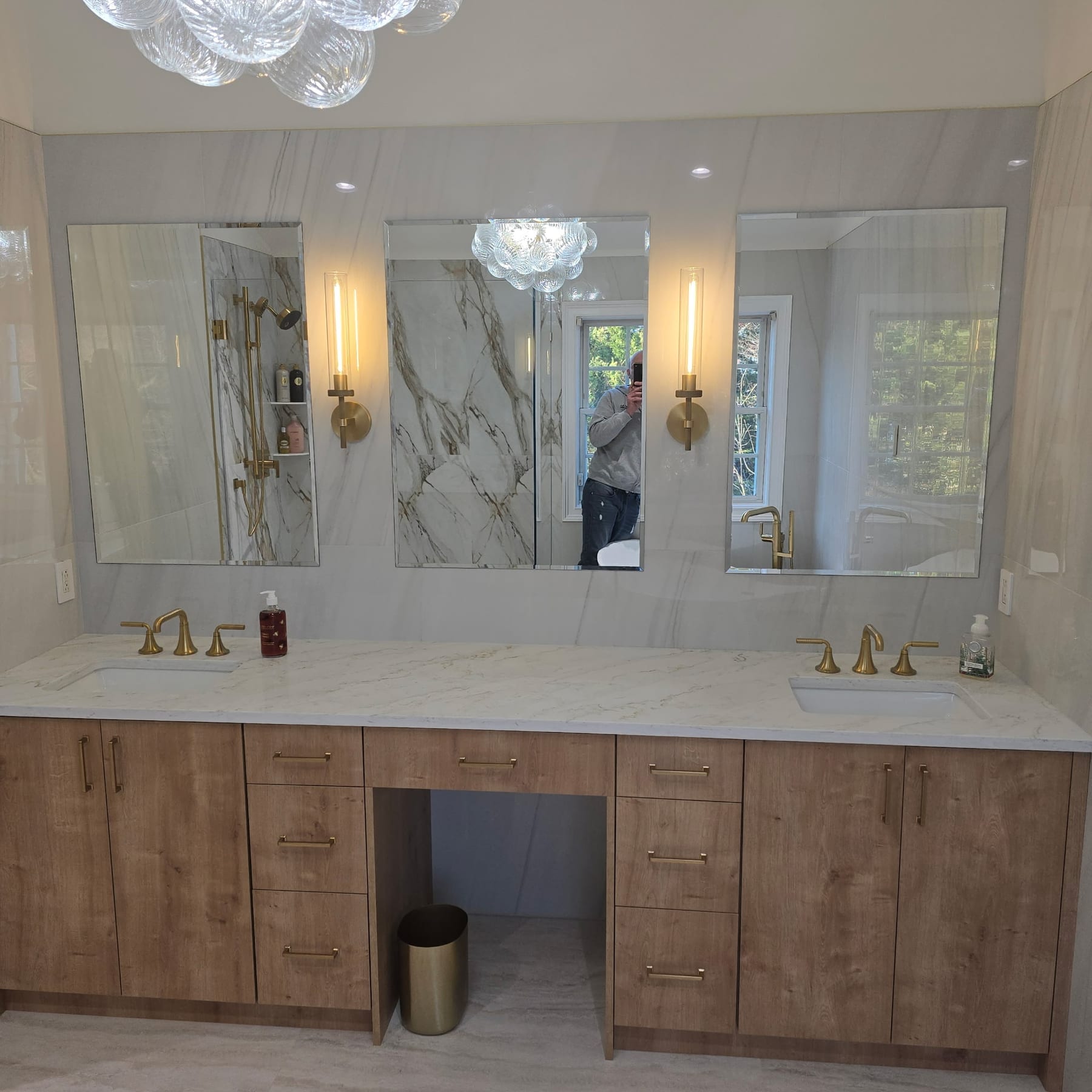 Custom wood double vanity with quartz counters and three lit mirrors