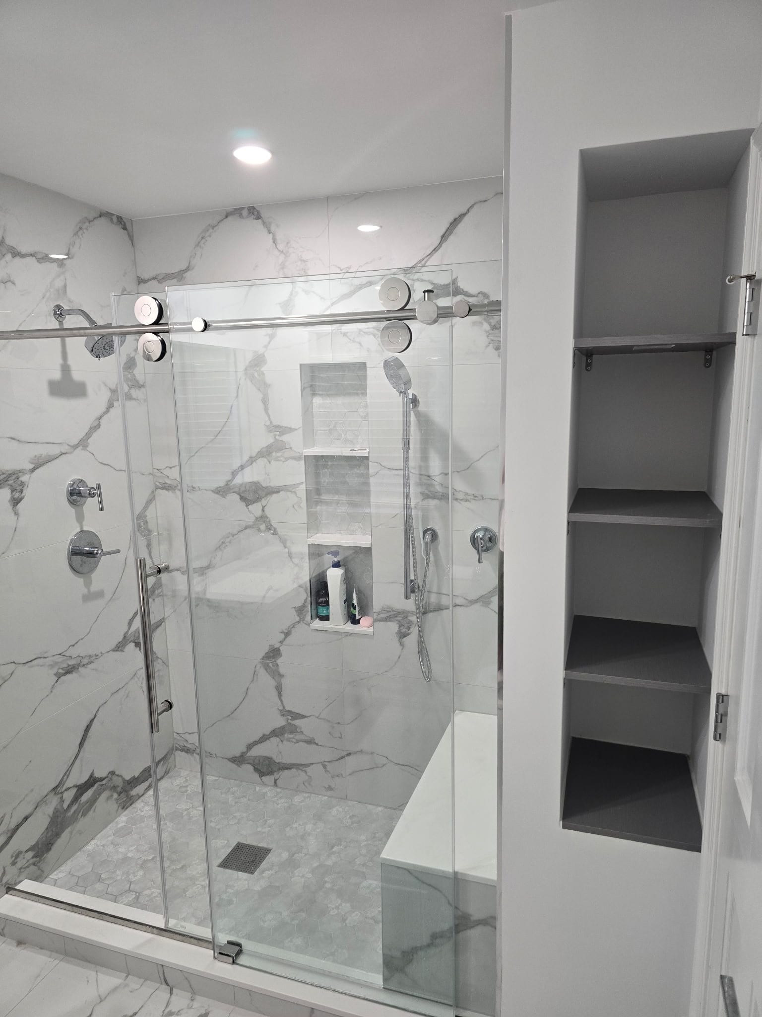 White Calacatta marble walk-in shower with built-in shelves