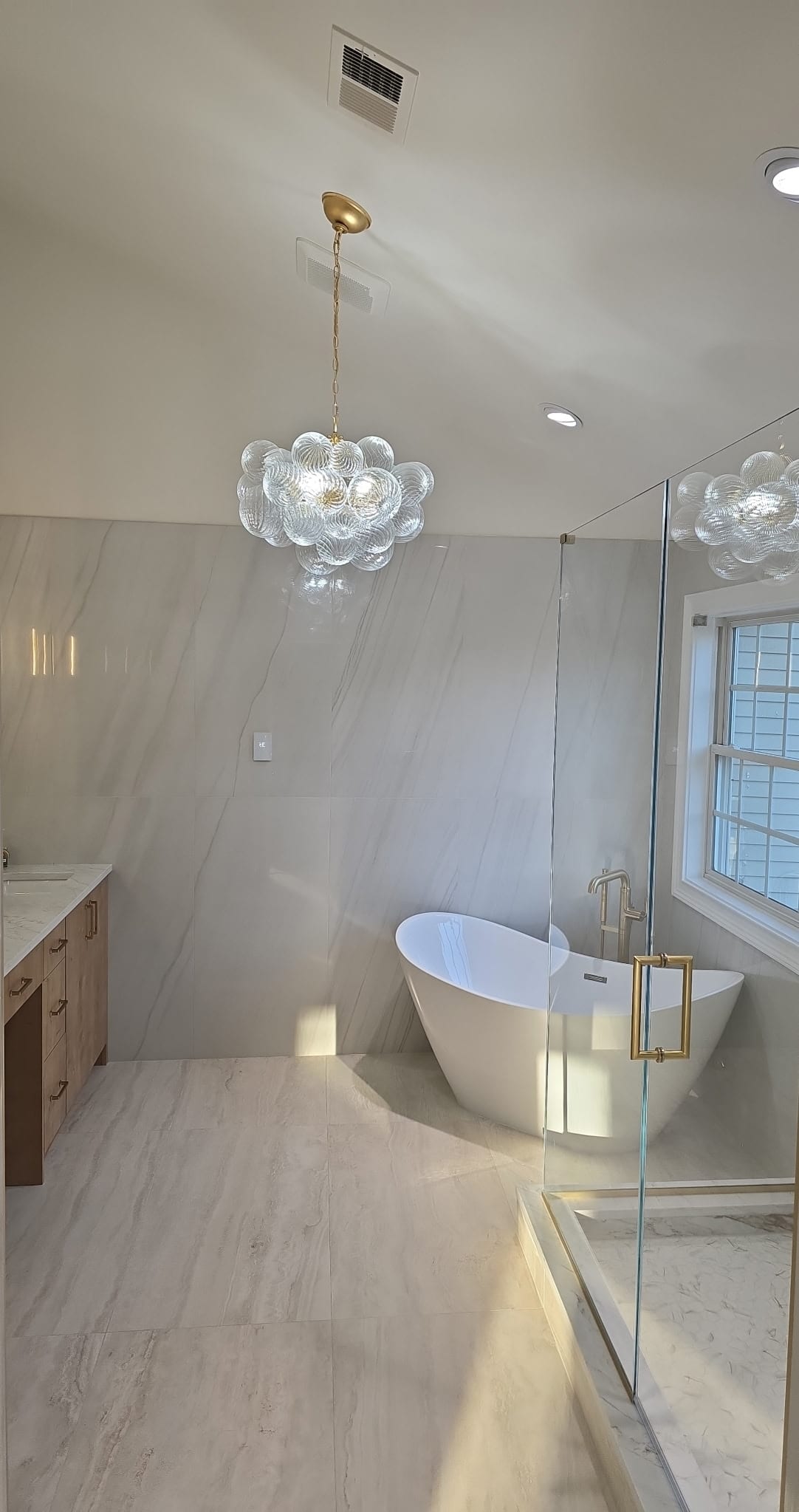 Master bath with bubble glass chandelier and freestanding tub