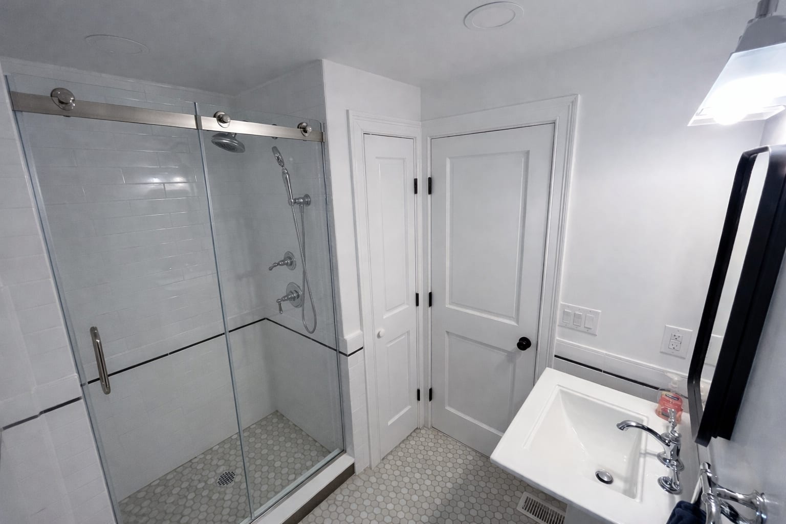 Renovated bathroom in the Victorian — clean white tile and glass shower